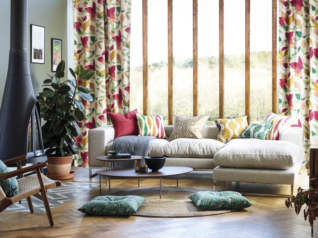 Белый диван с подушками стоит у окна