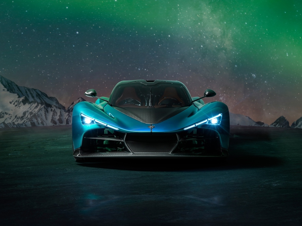 Голубой спортивный автомобиль Zenvo Aurora на фоне гор и полярного сияния