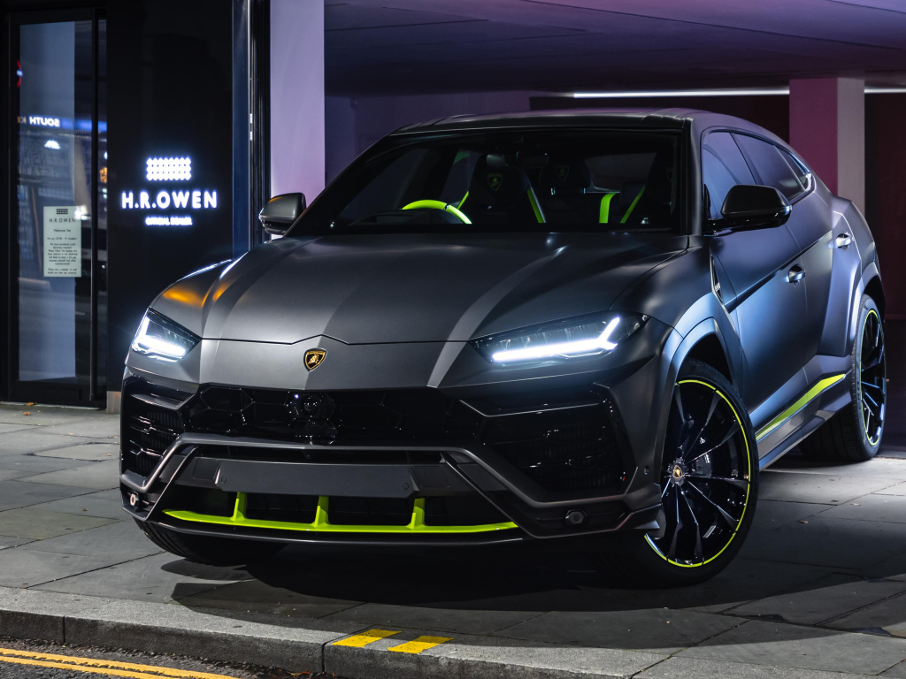 Серебристый Lamborghini Urus с включенными фарами