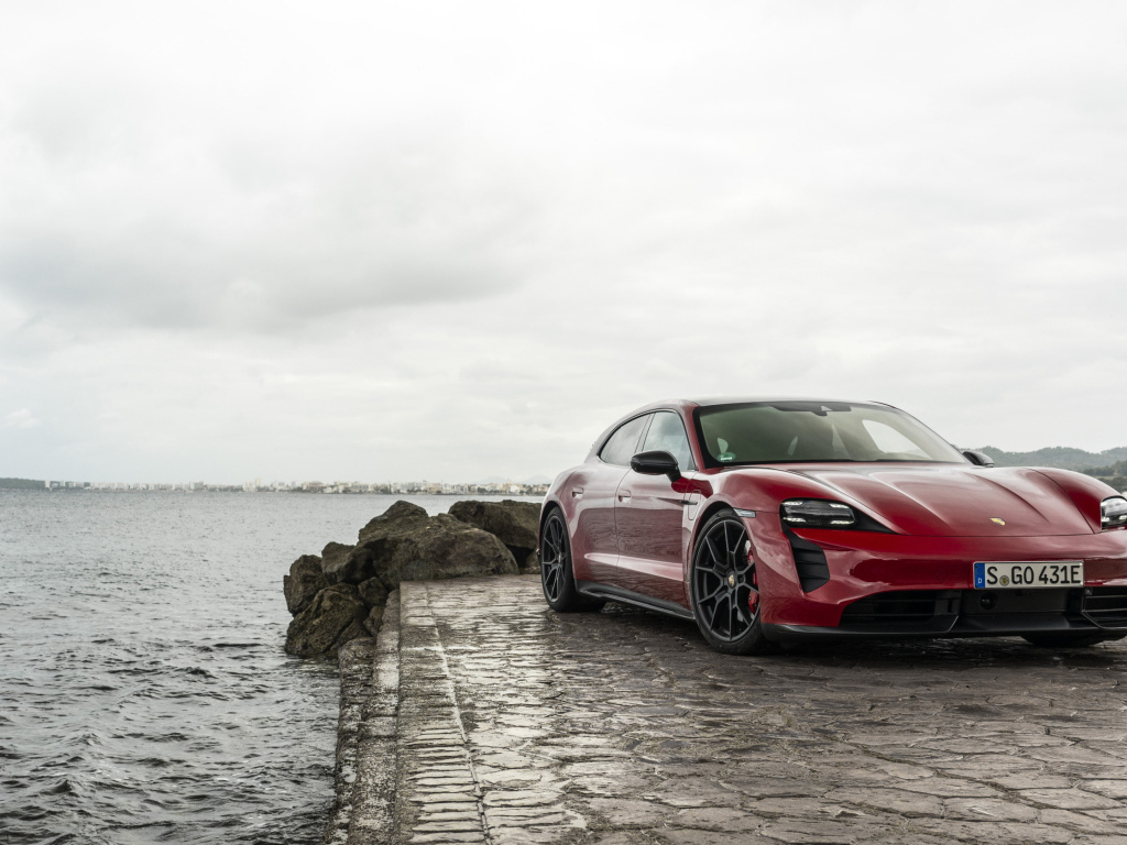 Красный автомобиль Porsche Taycan  у воды