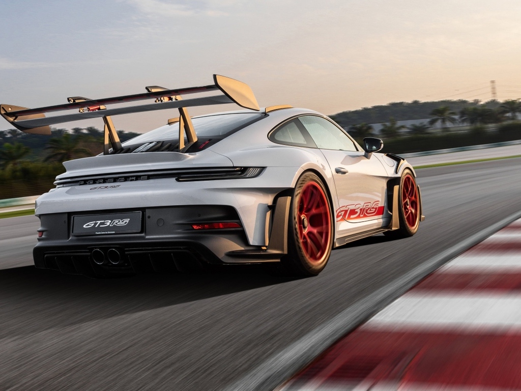 Серебристый спортивный автомобиль Porsche 911 GT3 RS Weissach Package 2023 года на трассе
