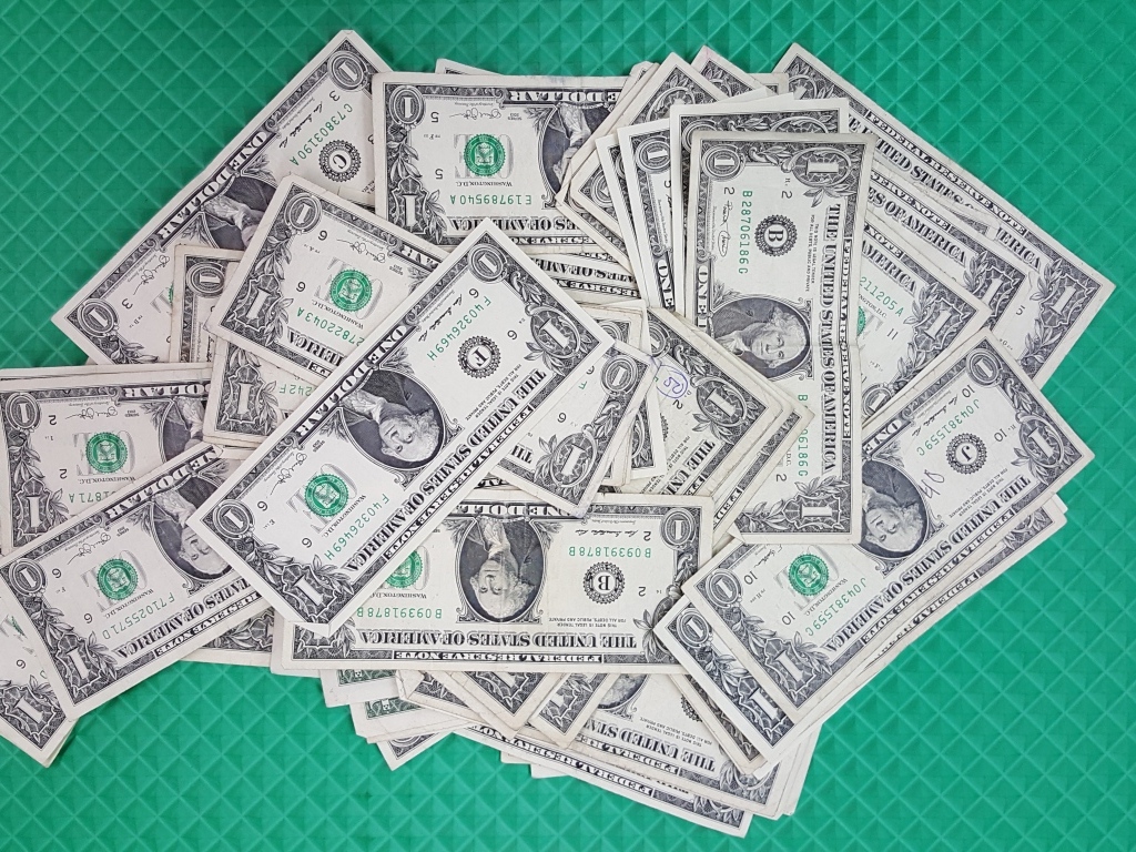 Много купюр в один доллар на зеленой поверхности