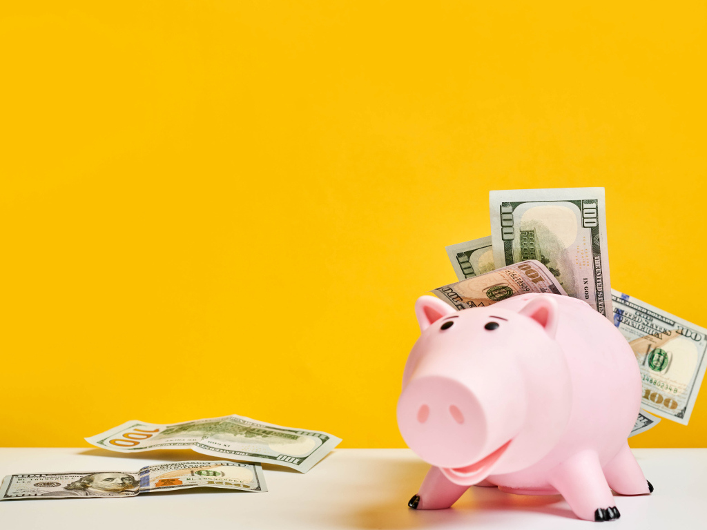 Pink pig piggy bank with banknotes on a yellow background