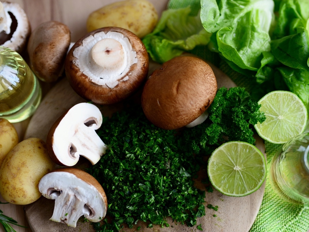 Грибы шампиньоны на столе с лаймом, картофелем и зеленью 