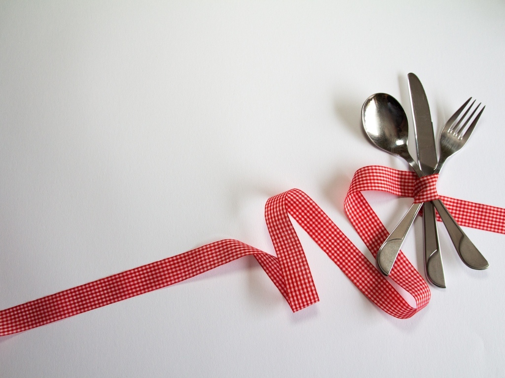 Столовые приборы перевязаны лентой на сером фоне