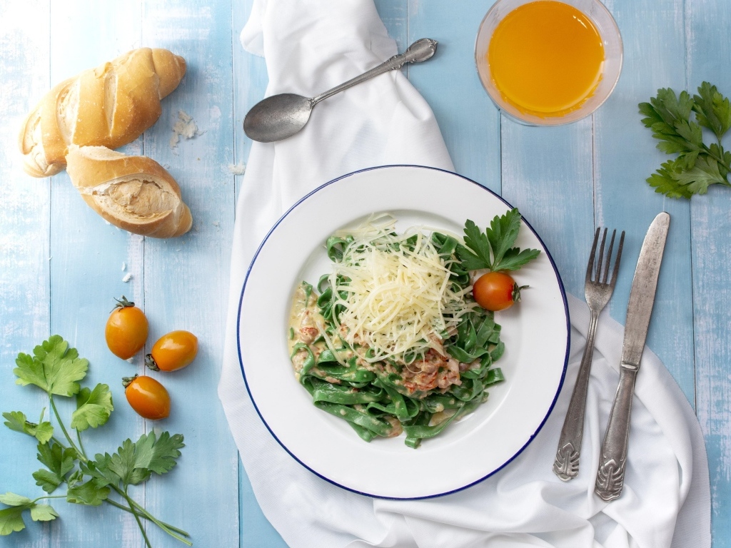 Зеленая лапша с сыром на столе с хлебом и зеленью