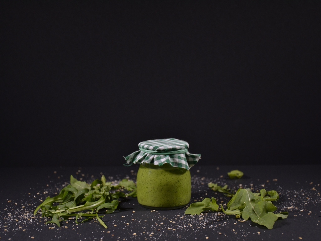 Банка соуса песто на черном фоне