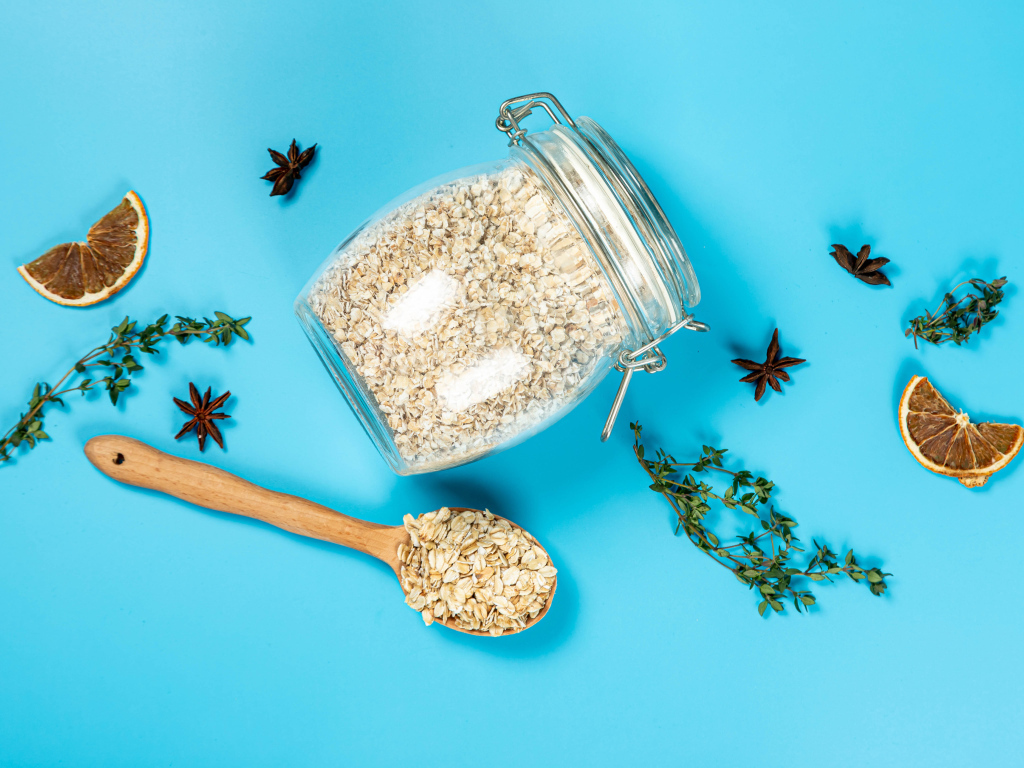 Банка с овсяными хлопьями и ложкой на голубом фоне