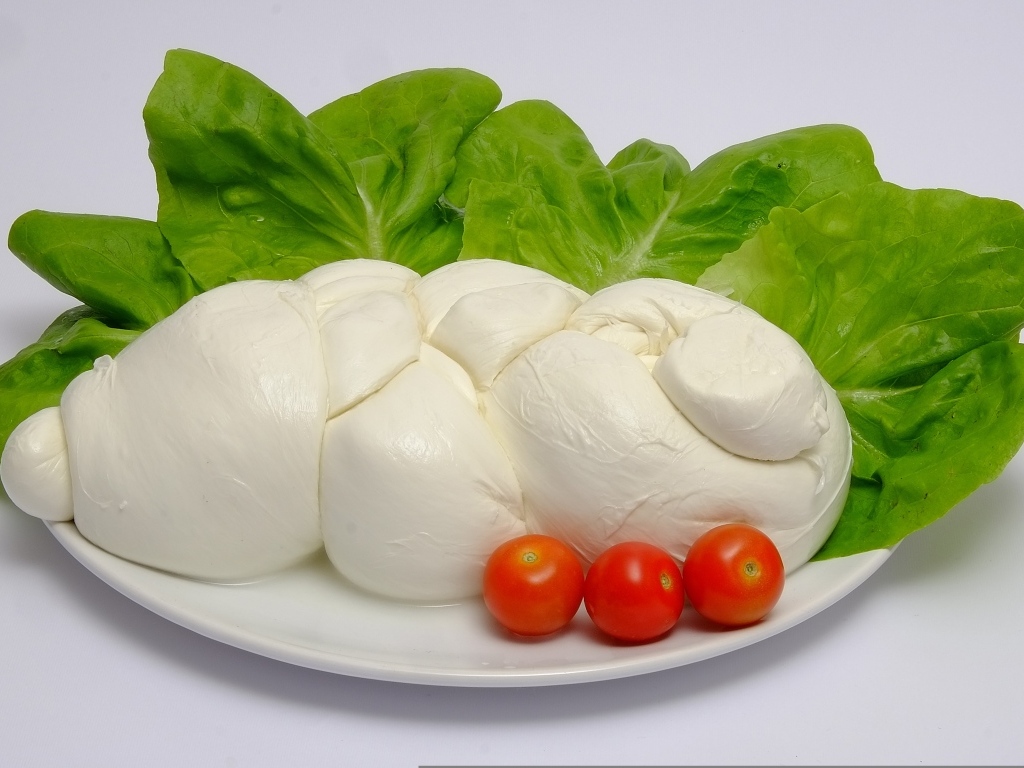 Сыр моцарелла на тарелке с листьями салата и помидорами