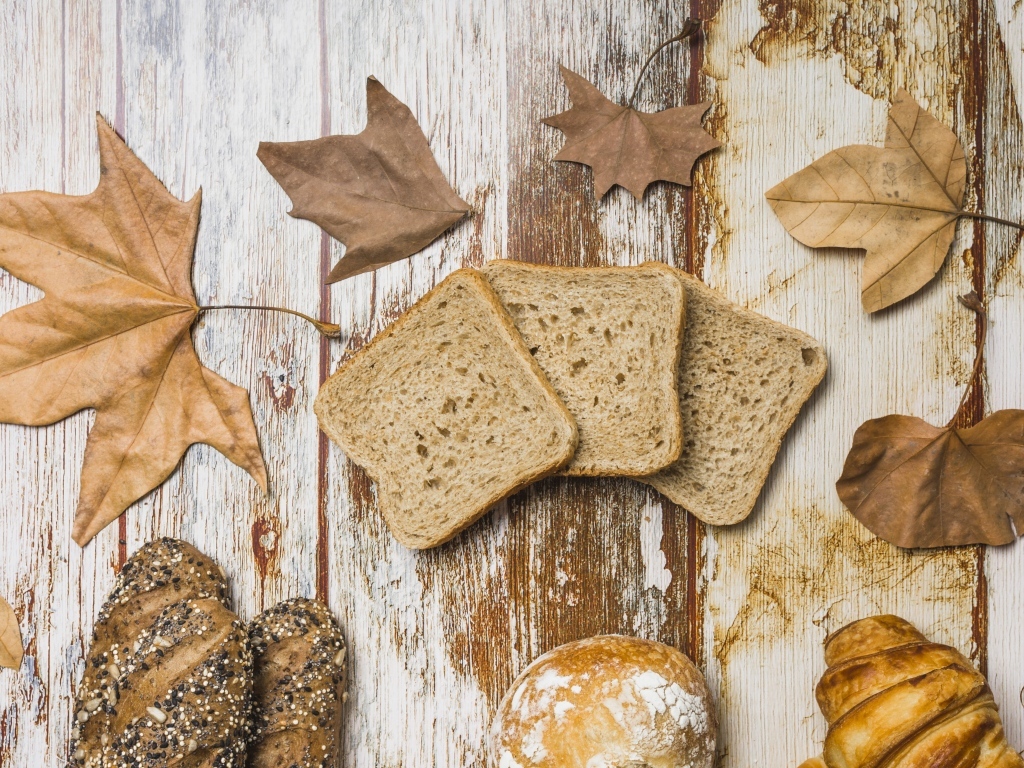 Куски хлеба с листьями на деревянном столе