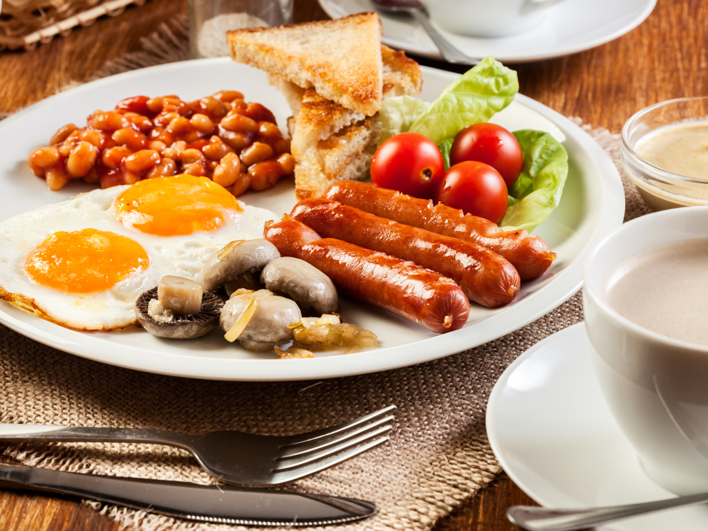 Яичница, сосиски и овощи на тарелке на завтрак