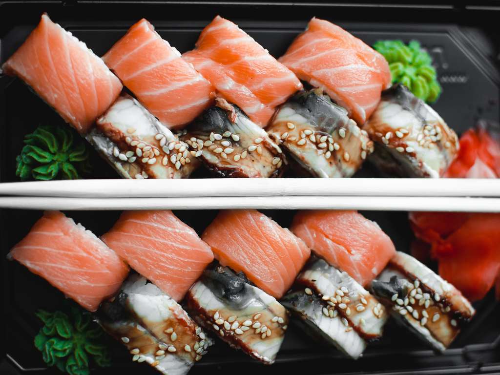 Суши с рыбой на черной тарелке с палочками