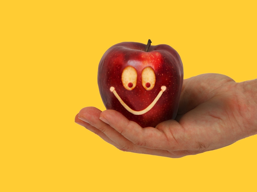 Яблоко на ладони на желтом фоне