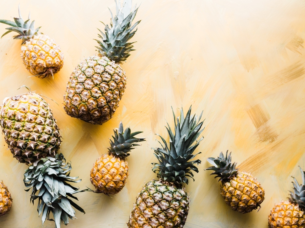 Много ананасов на желтом фоне