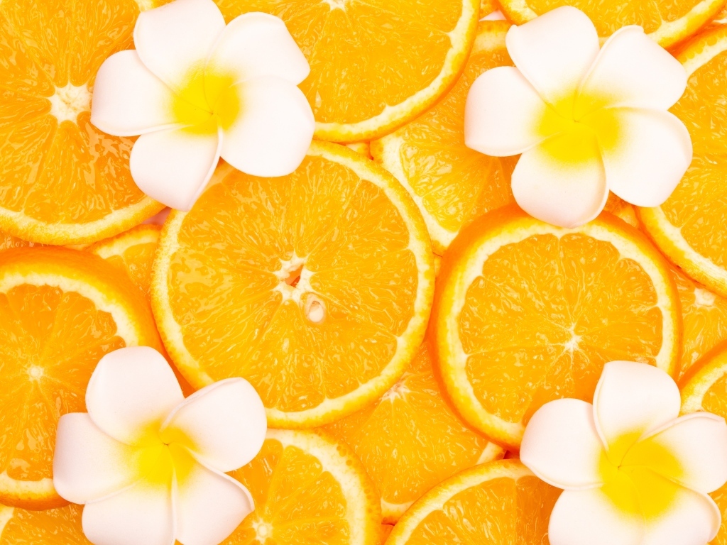 Кружочки апельсина с цветами плюмерии крупным планом