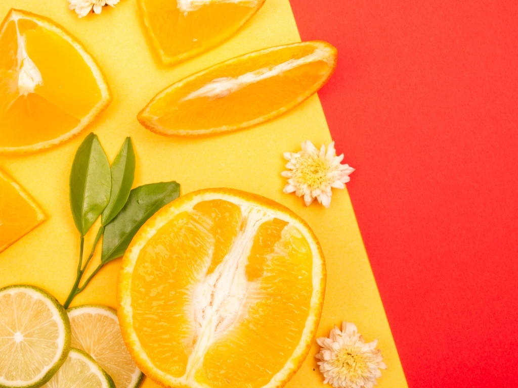 Кусочки апельсина и лайма на разноцветной поверхности 