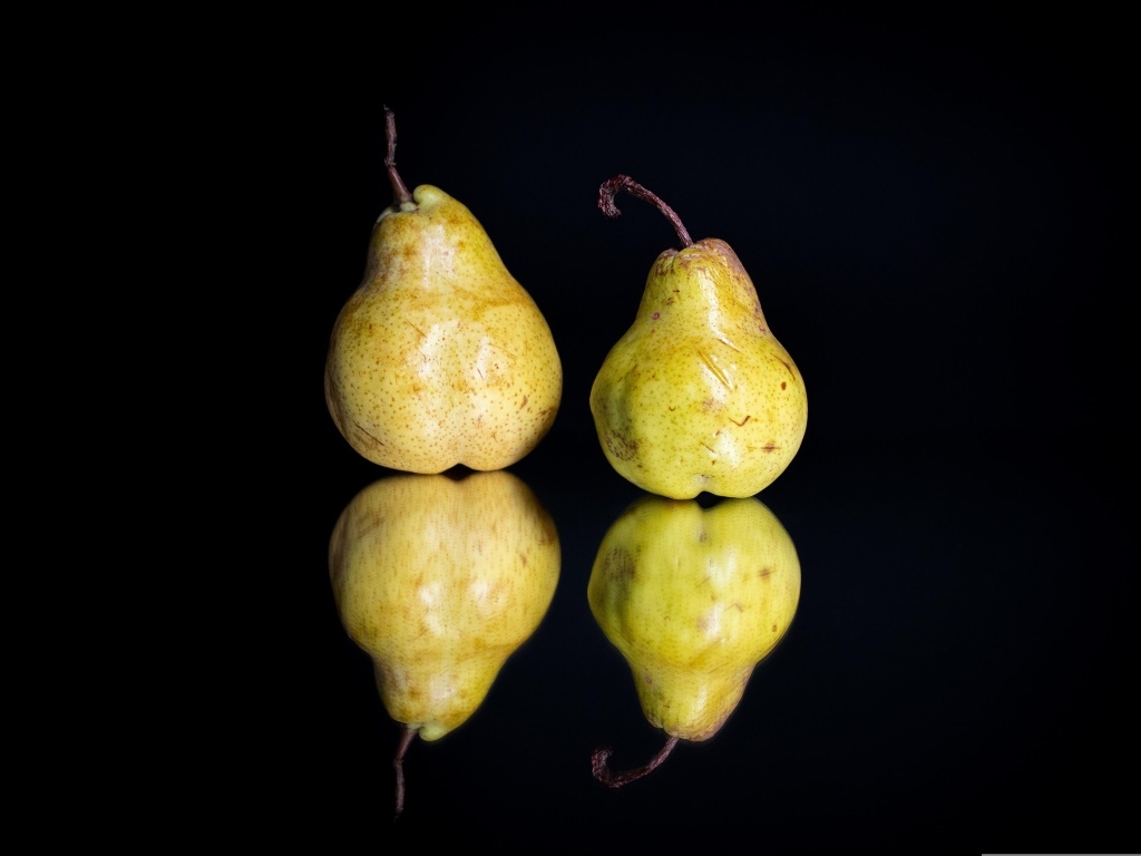 Две груши отражаются в зеркальной поверхности 