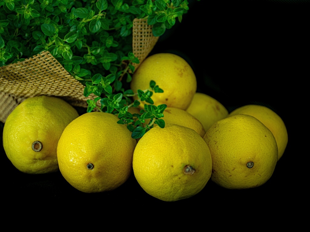 Желтые лимоны с зеленью на столе