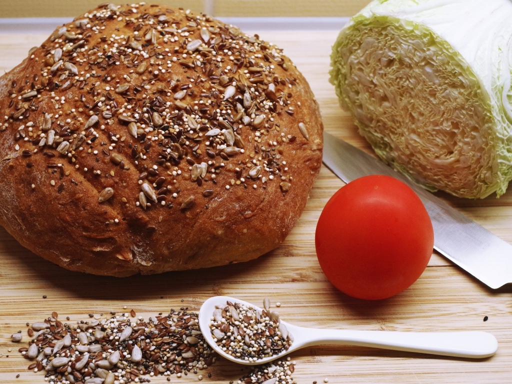 Буханка хлеба на столе с капустой и помидором