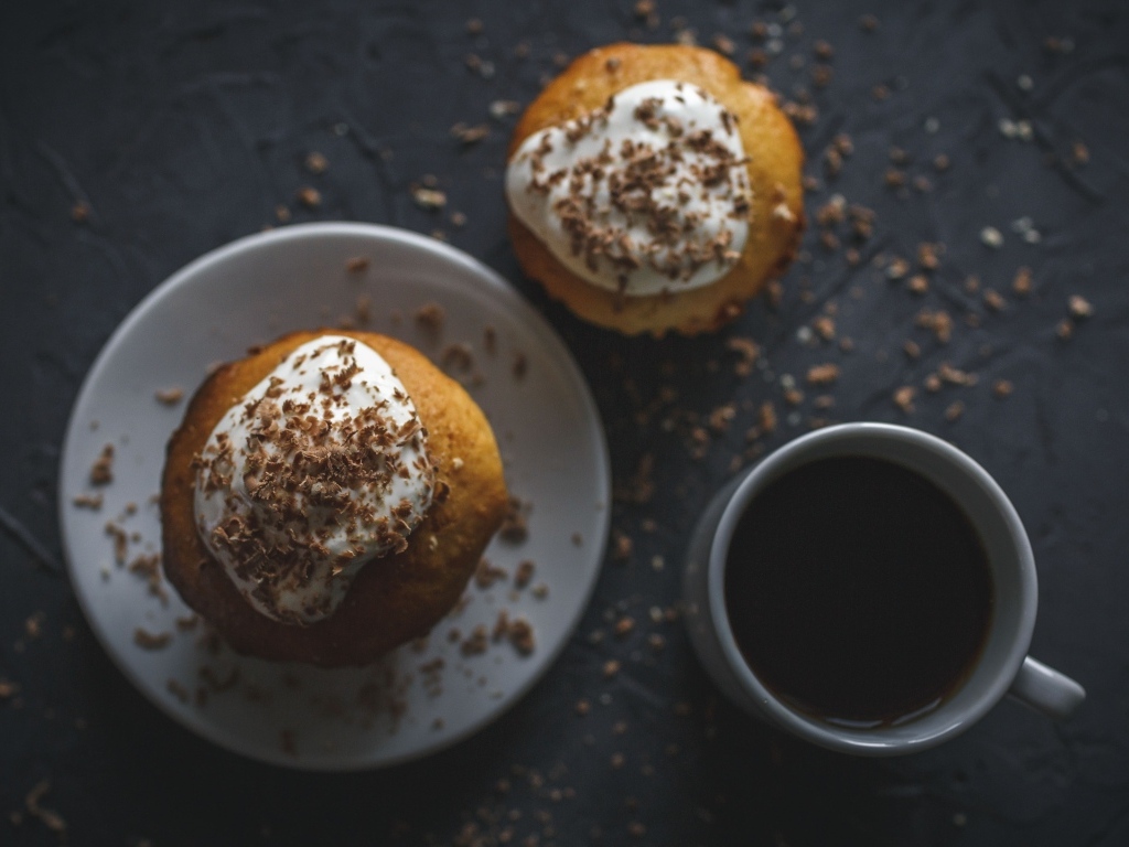 Пирожное в тертым шоколадом на столе с чашкой кофе