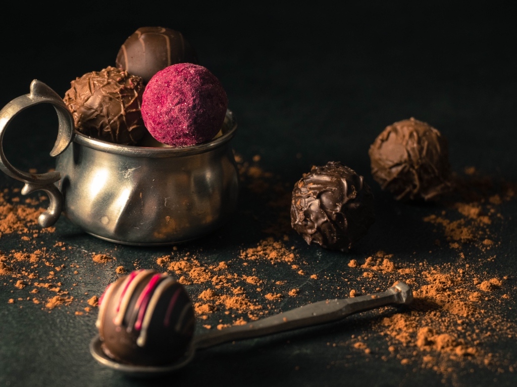 Шоколадные конфеты с железной чашкой на черном фоне