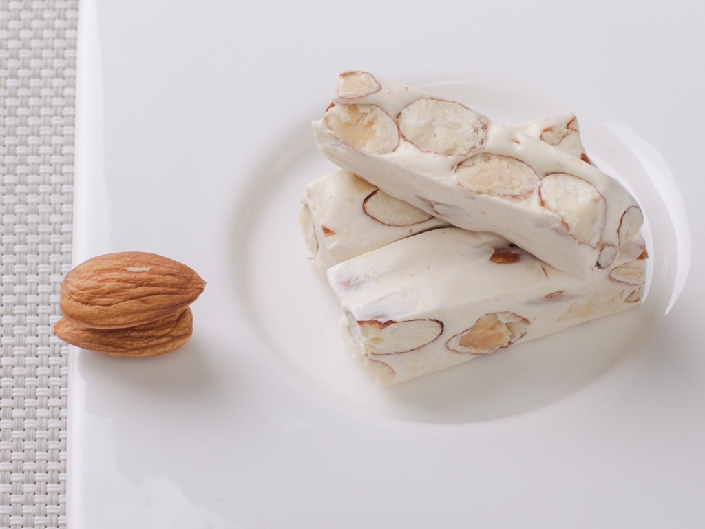 Десерт нуга с миндальными орехами на тарелке 