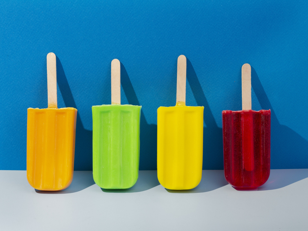 Разноцветное фруктовое мороженое на фоне голубой стены