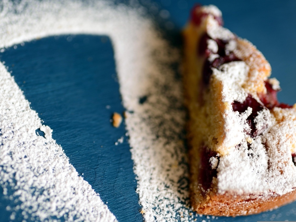 Кусок пирога с ягодами на столе с сахарной пудрой