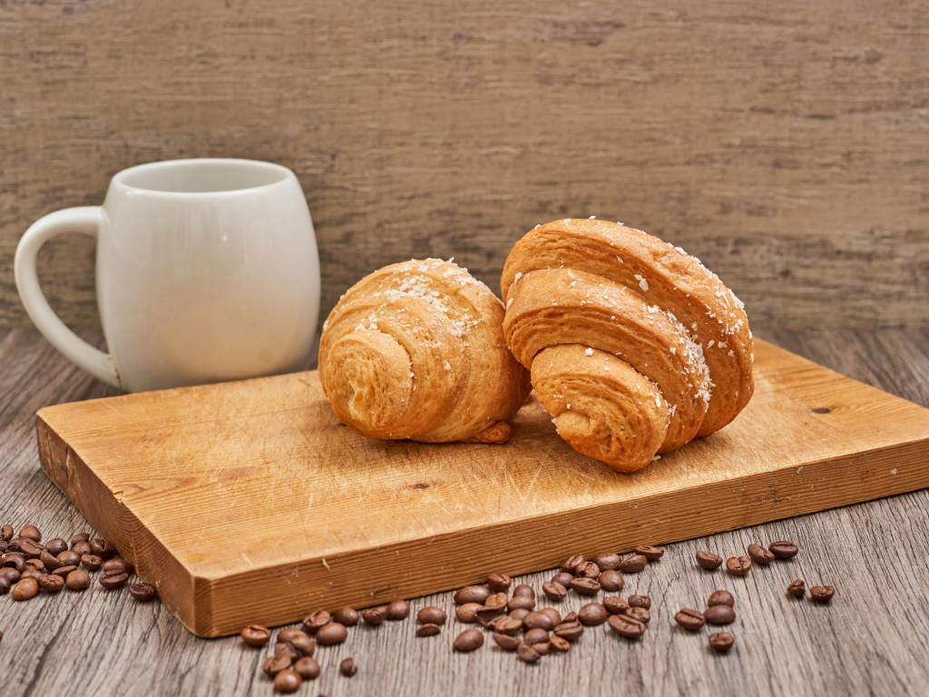 Два круассана на доске с кофейными зернами
