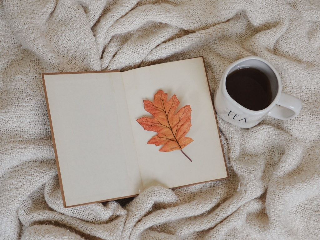 Книга, желтый лист и чашка кофе с пледом