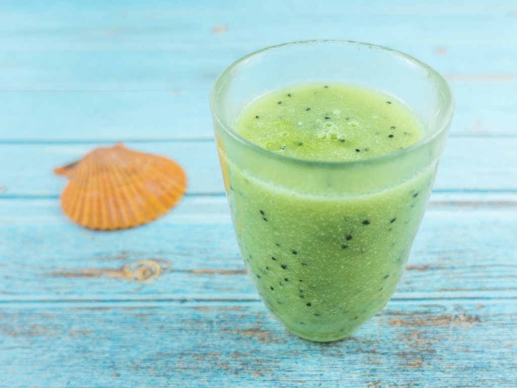 Фруктовый зеленый смузи на голубом столе