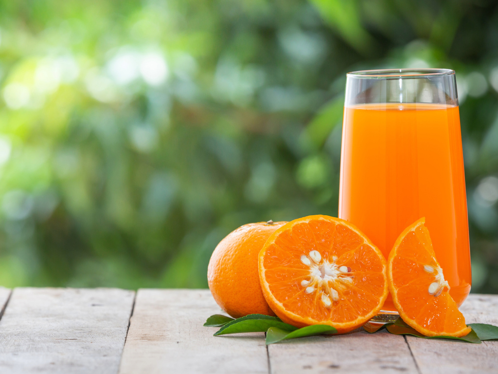 Стакан сока с апельсинами на деревянном столе