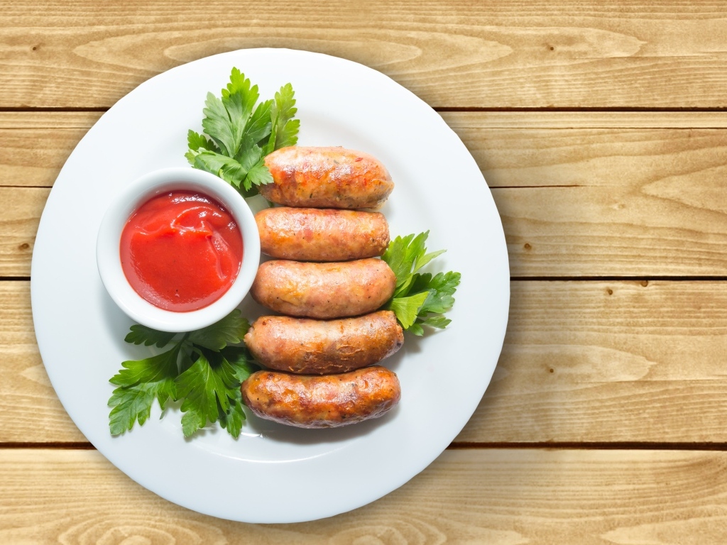 Сардельки на тарелке с соусом и петрушкой