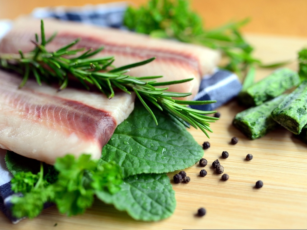 Свежая рыба на доске с зеленью и специями