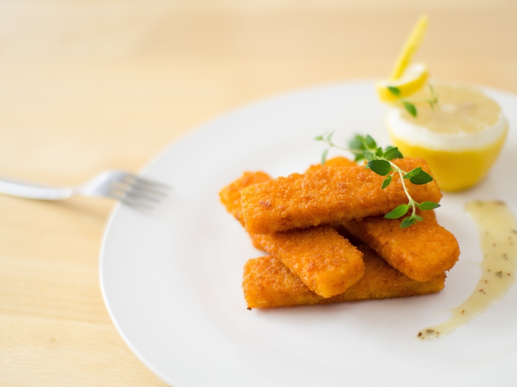 Жареные рыбные палочки на тарелке с лимоном