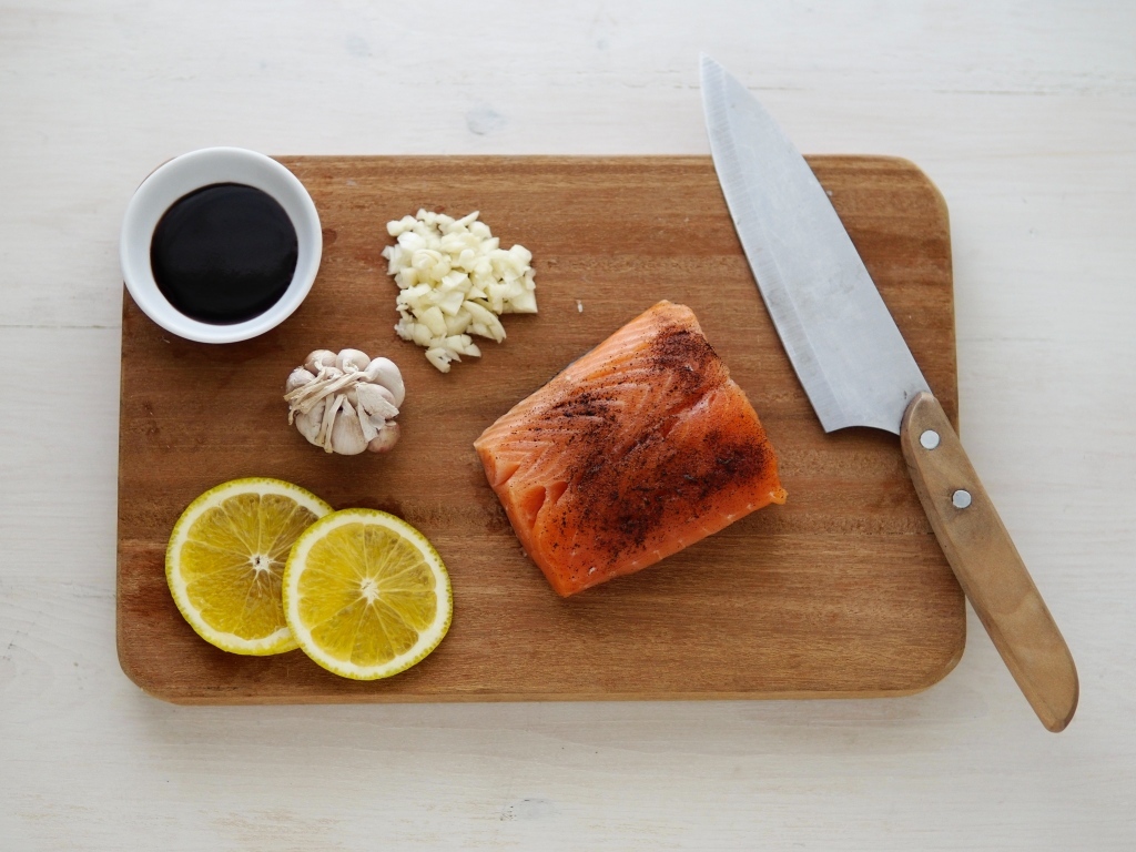 Кусок красной рыбы на доске с лимоном и чесноком