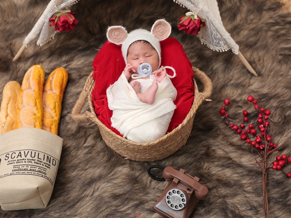 Ребенок спит в корзине с соской во рту