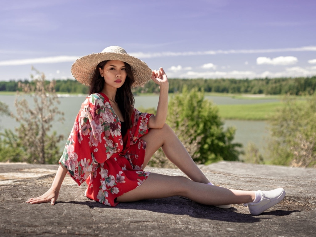 Девушка азиатка в шляпе лежит на камне