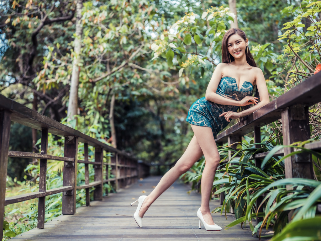 Девушка азиатка в коротком платье у перил на мосту