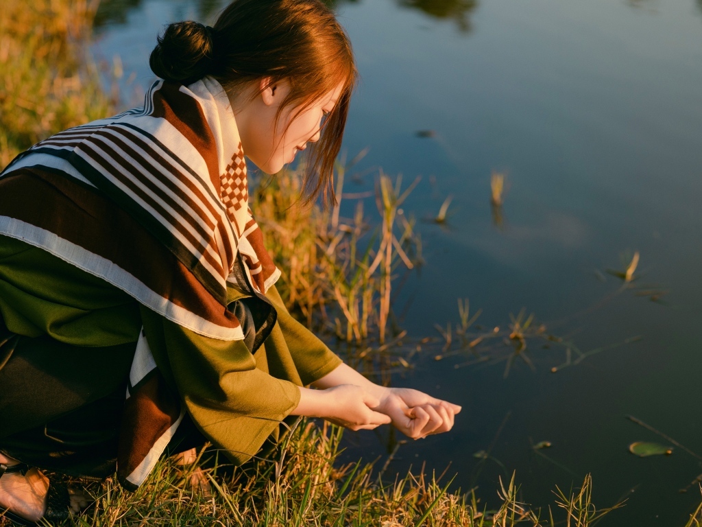 Девушка азиатка сидит у пруда