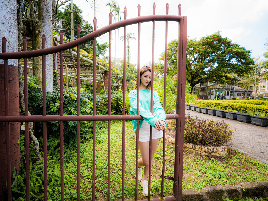 Девушка азиатка стоит у железных ворот 