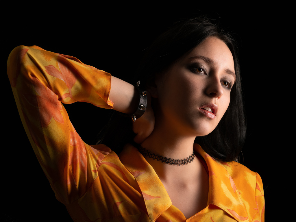 Красивая девушка шатенка с рукой в волосах на черном фоне