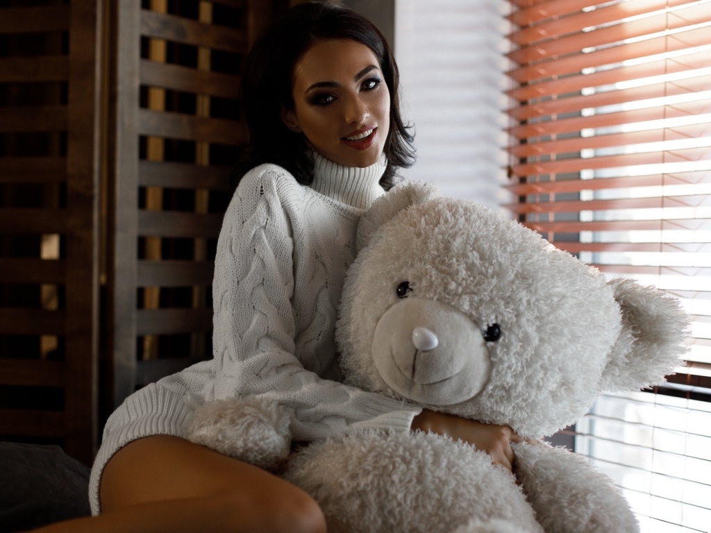Красивая девушка в свитере с медведем у окна