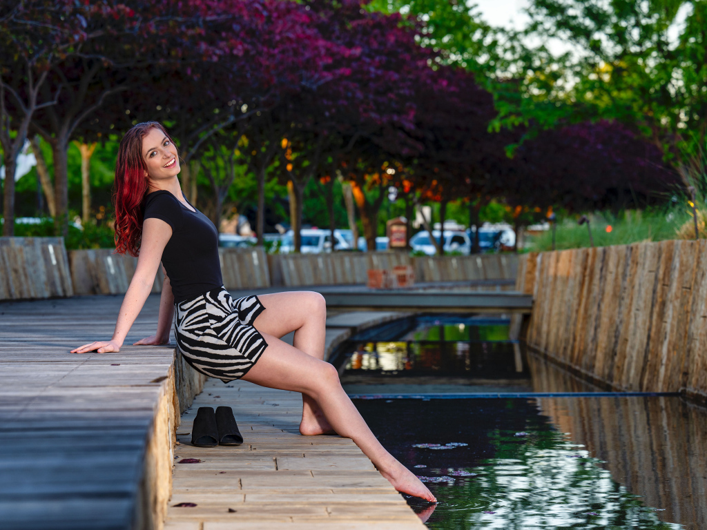 Красивая девушка опустила ноги в воду