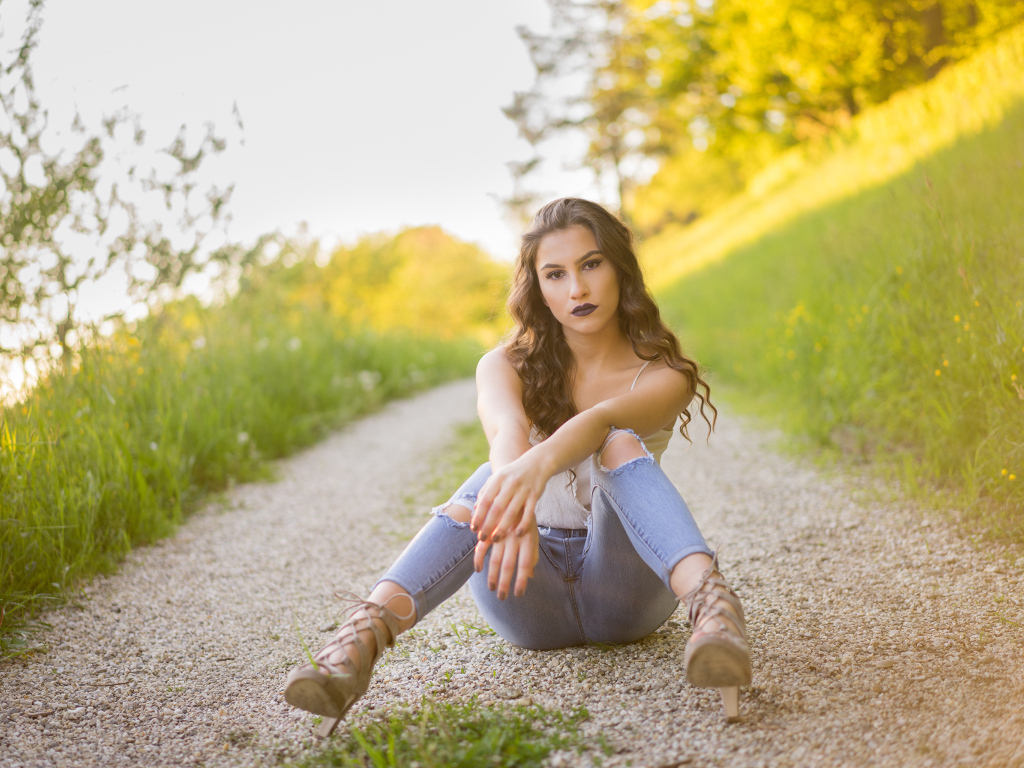 Красивая девушка сидит на дороге летом