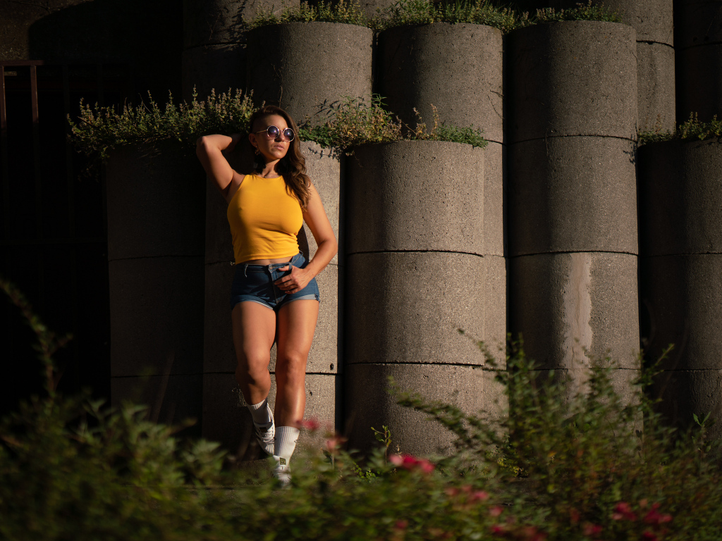 Красивая девушка в очках стоит у стены