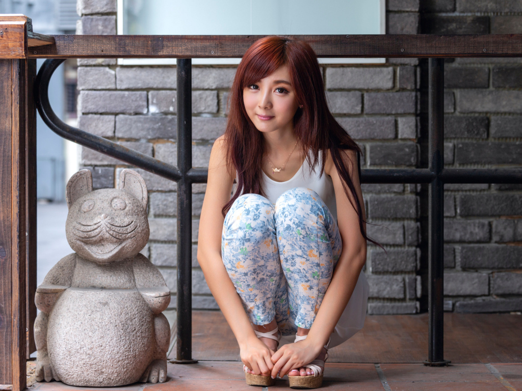 Милая девушка азиатка позирует со статуэткой