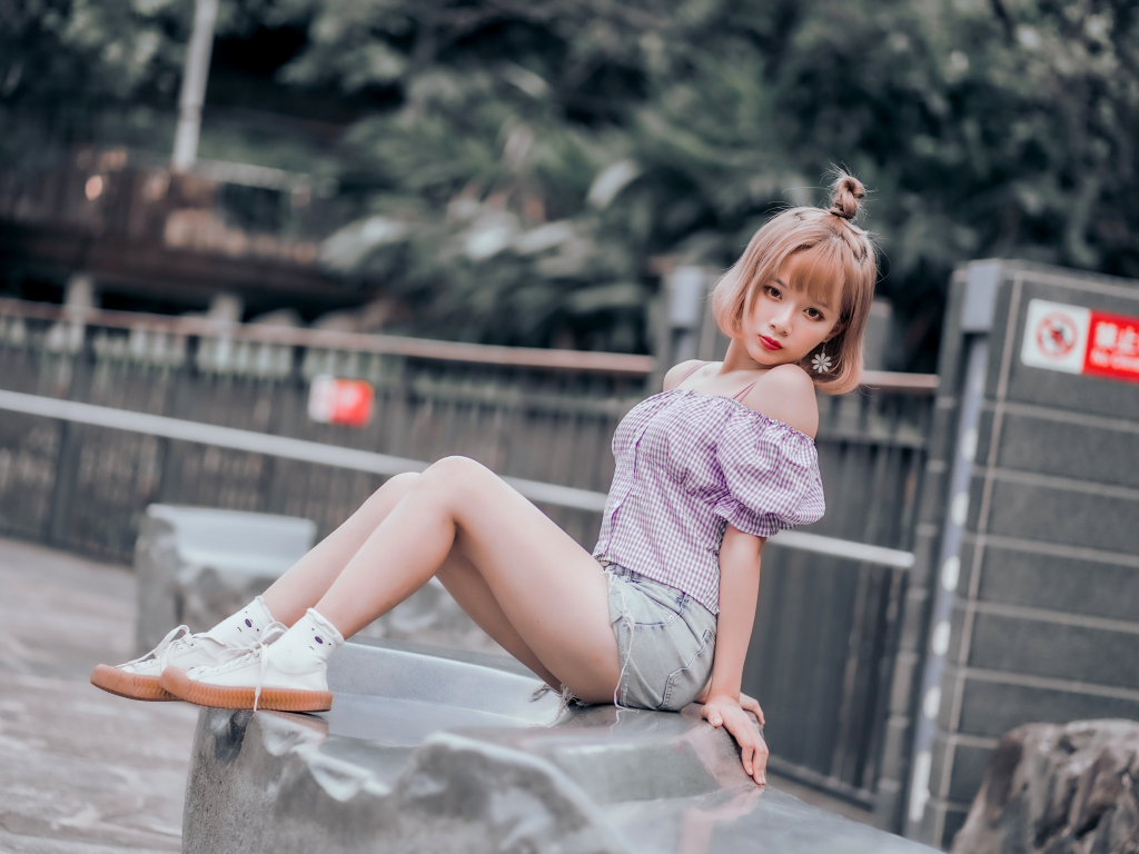 Милая девушка азиатка сидит на камне