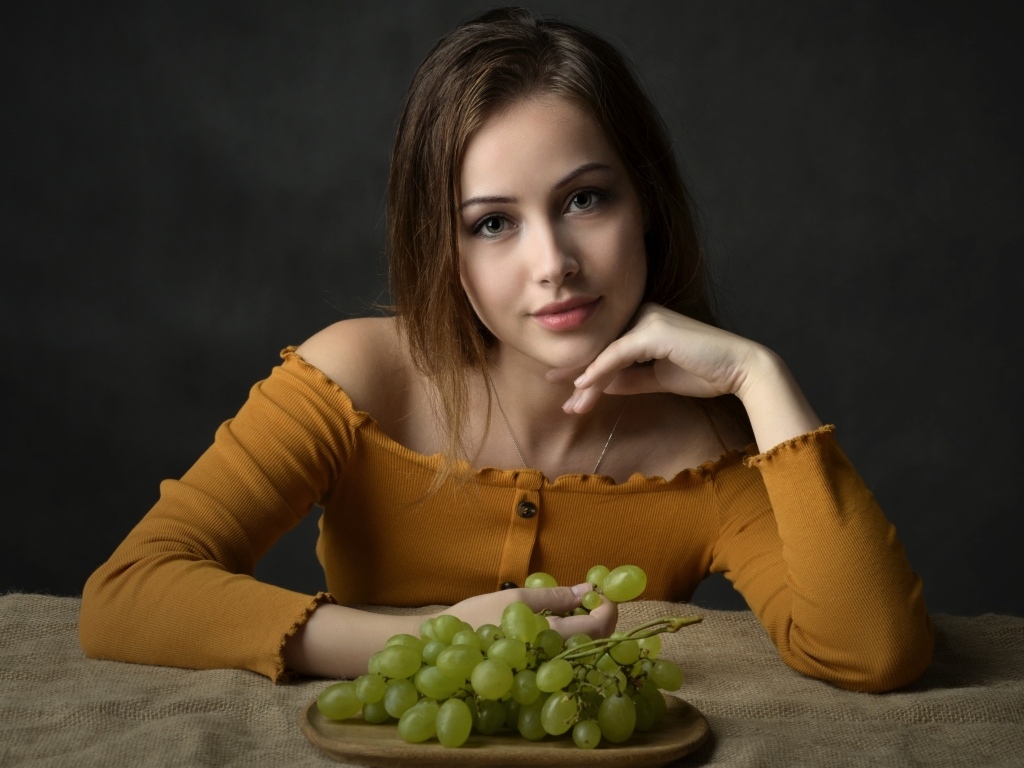 Милая шатенка ест белый виноград