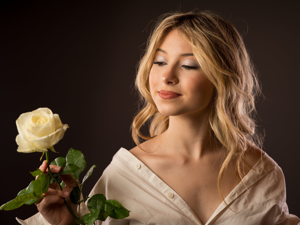 Милая девушка в рубашке с розой в руках